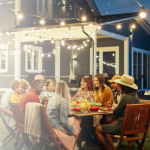 various people sitting around a patio table in a backyard